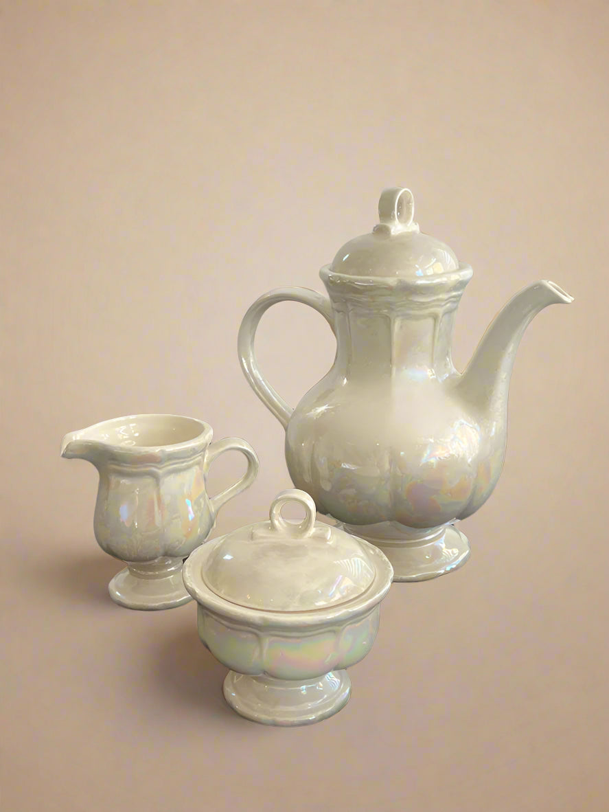 White ceramic tea set on a black surface with a white background