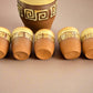 Set of six wooden cups with decorative patterns on a dark fabric background