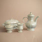 Set of white ceramic teaware on a black surface with a gray background